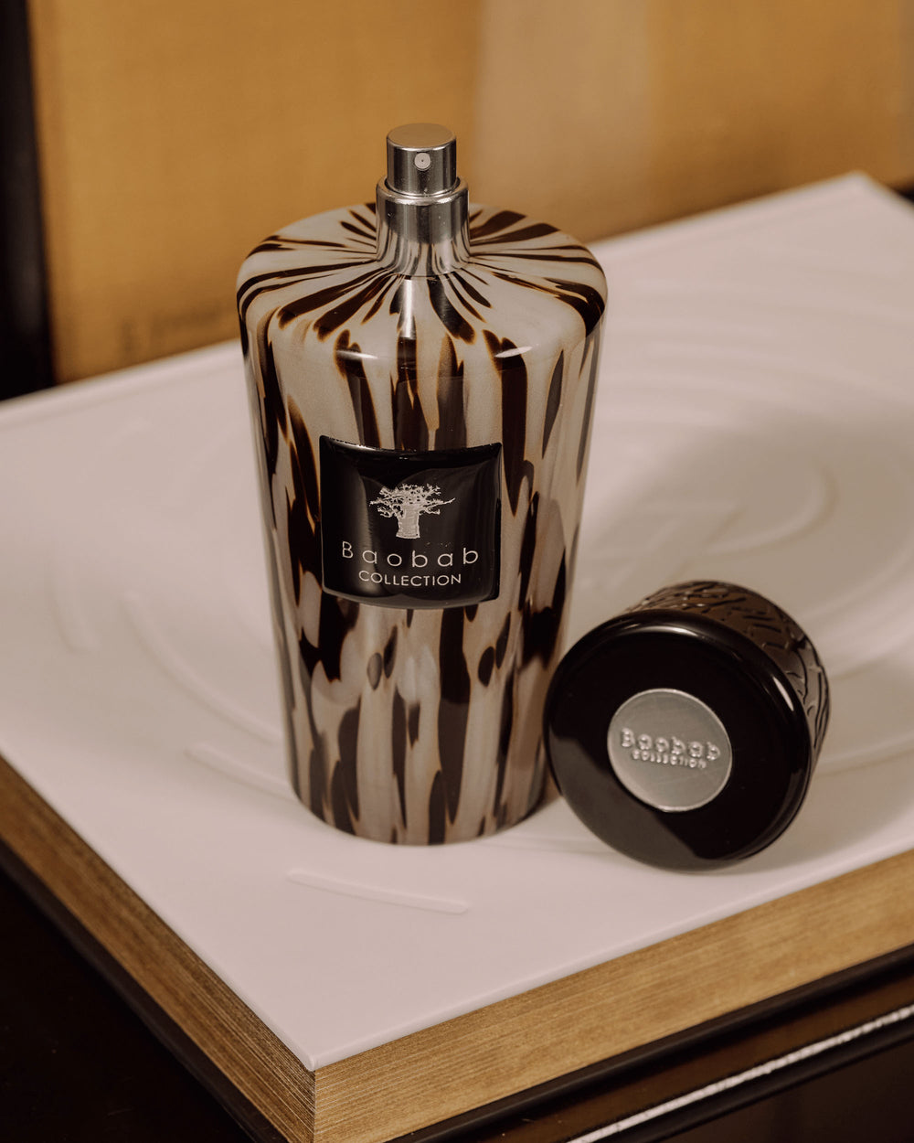 Ambientador en spray Baobab Collection Black Pearls, frasco con diseño marmolado negro y beige y tapa aparte.