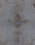 Alfombra vintage persa en detalle: motivo central descolorido sobre base gris-azul.