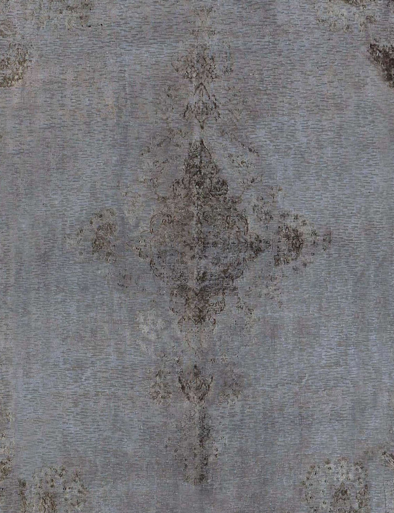 Alfombra vintage persa en detalle: motivo central descolorido sobre base gris-azul.