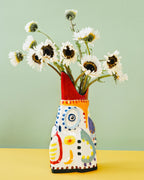 Jarrón cerámico pintado a mano con flores blancas, base naranja y motivos azules