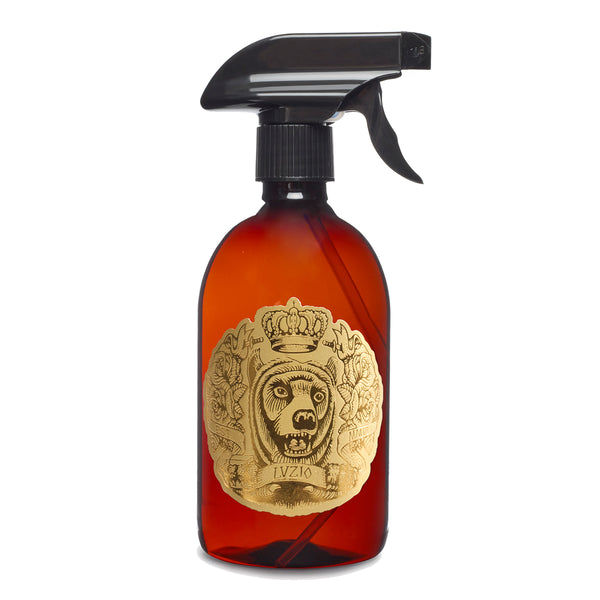 Ambientador en spray LUZIO en frasco ámbar con pulverizador negro y etiqueta dorada.