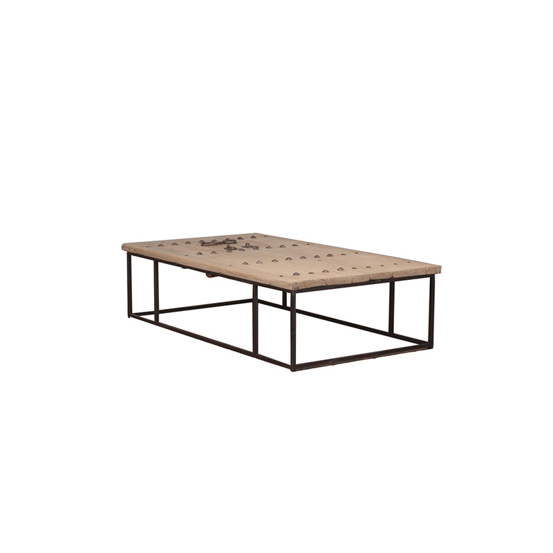 Mesa de centro de madera clara con base de hierro negro y placa decorativa con remaches