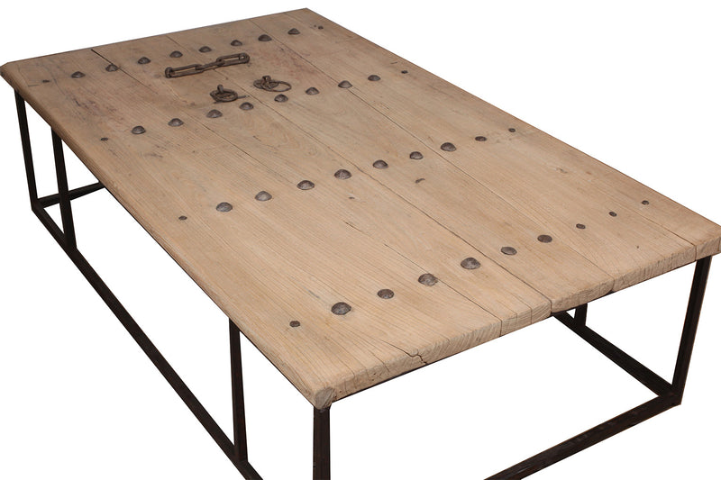 Mesa de centro de madera clara con placa metálica decorativa y base de hierro negro