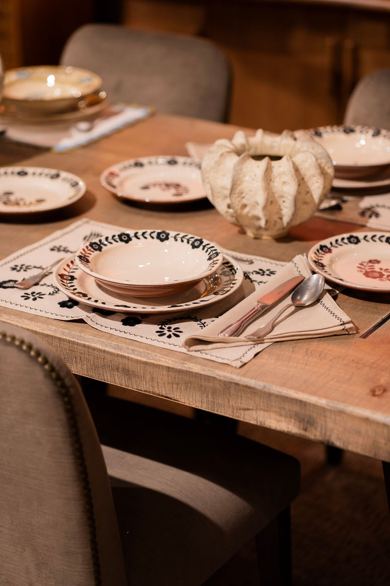 Plato hondo Viana en mesa, con borde floral negro y diseño sobre base clara