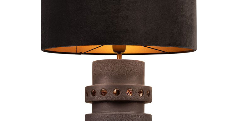 Detalle de la base de metal bronce con orificios y pantalla negra con interior cálido