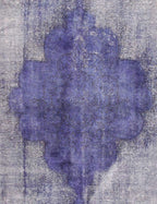 Alfombra vintage persa: detalle de medallón azul/morado con fondo gris jaspeado.