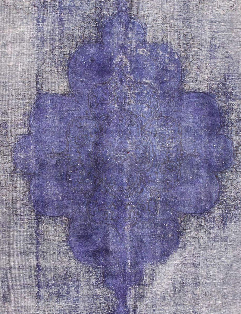 Alfombra vintage persa: detalle de medallón azul/morado con fondo gris jaspeado.