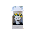 Vela decorativa con cabeza blanca, bigote y limones sobre hojas