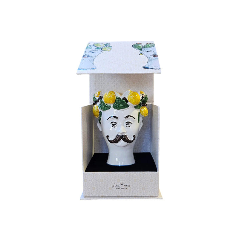 Vela decorativa con cabeza blanca, bigote y limones sobre hojas