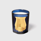 Vela en frasco de vidrio azul con mecha visible y motivos dorados grabados