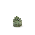 Vela perfumada en recipiente cerámico verde con tapa esculpida de animal