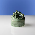Vela perfumada verde con tapa esculpida de animal y recipiente esmaltado