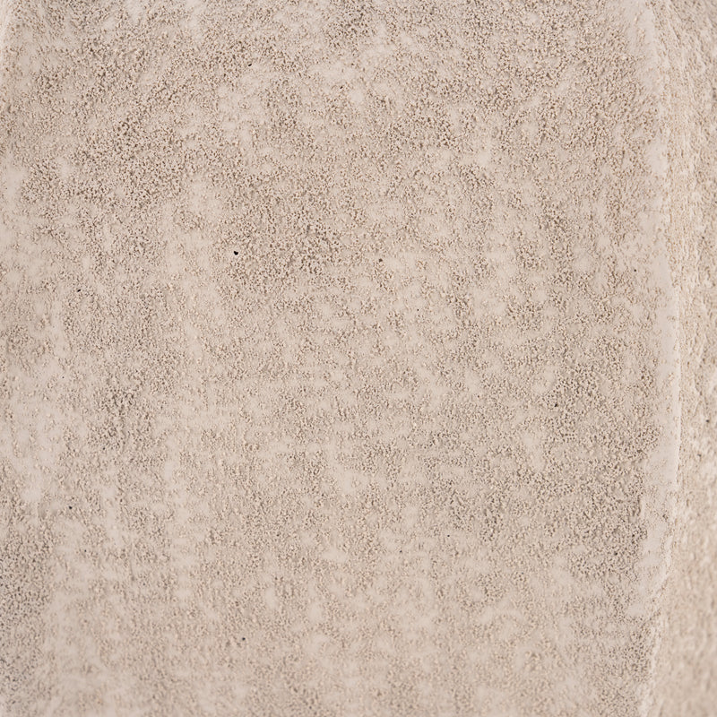 Jarrón de cemento beige, detalle de textura rugosa tipo grano fino.