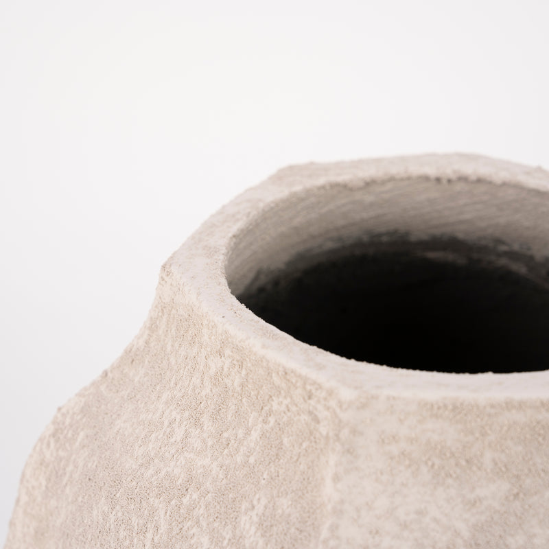 Jarrón de cemento beige con boca ancha y borde con textura, interior oscuro.