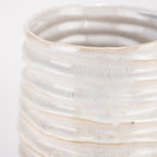 Jarrón de cerámica blanco, close-up del cuerpo con bandas y salpicaduras decorativas.