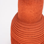 Jarrón de cerámica terracota con textura rugosa y anillos ondulados en el cuerpo