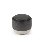 Vela perfumada decorativa en recipiente cilíndrico oscuro con tapa redonda negra
