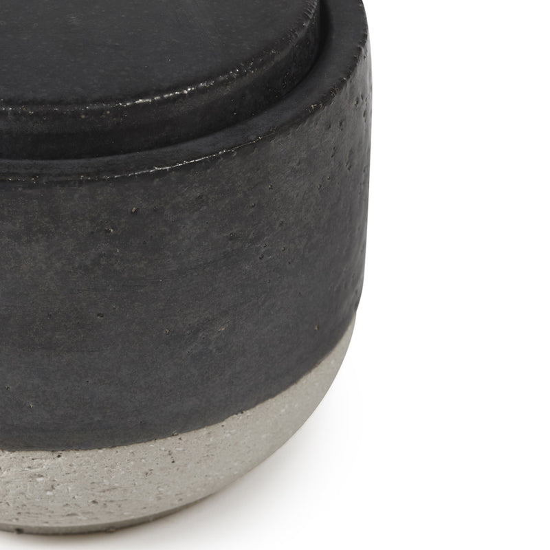 Detalle del recipiente de vela perfumada con parte superior oscura y base gris clara