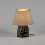 Lámpara de mesa con pantalla beige iluminada y base de tronco verde texturizado