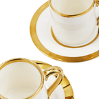 Taza de espresso blanca con borde dorado y asa, sobre plato a juego