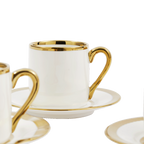 Taza de espresso blanca con asa dorada y plato redondo con borde dorado
