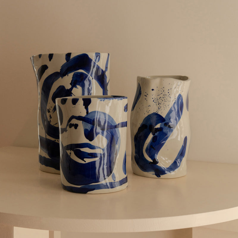 Conjunto de jarrones de cerámica con decoración abstracta azul en mesa