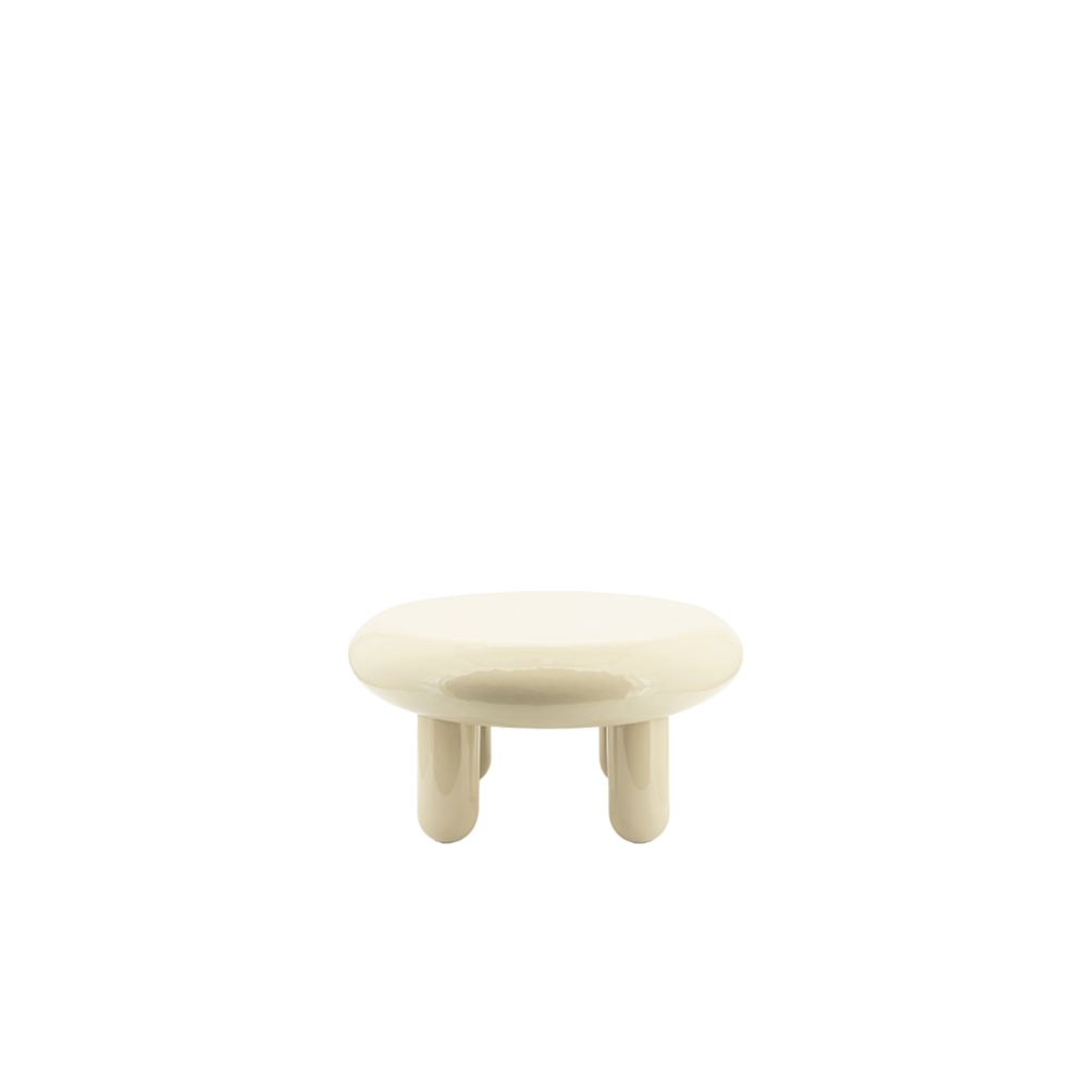 Mesa de centro redonda de color beige con sobre brillante y cuatro patas cortas.