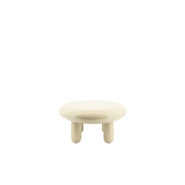 Mesa de centro redonda de color beige con sobre brillante y cuatro patas cortas.