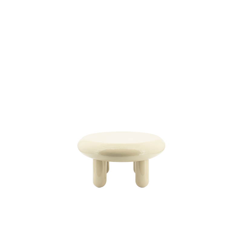 Mesa de centro redonda de color beige con sobre brillante y cuatro patas cortas.