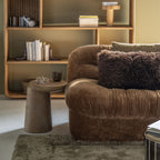 Sofá de tela mostaza con brazo acolchado y cojín decorativo, vista de tres cuartos.