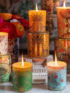 Vela en envase cilíndrico de colores con estampado floral, llama encendida, ORTIGIA.