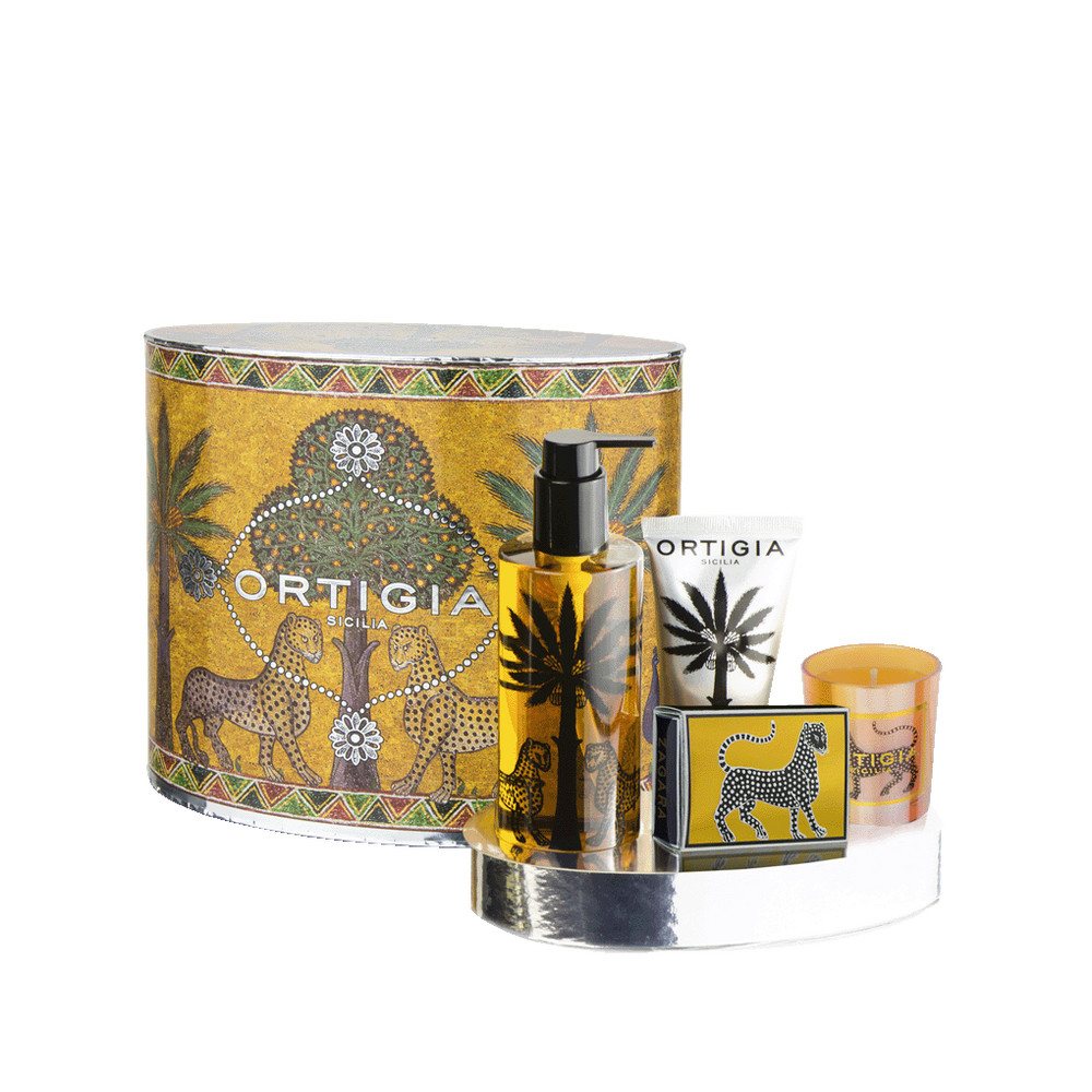 Set de regalo Ortigia con estuche cilíndrico dorado, botella negra y vela naranja.