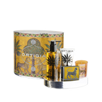 Set de regalo Ortigia con estuche cilíndrico dorado, botella negra y vela naranja.
