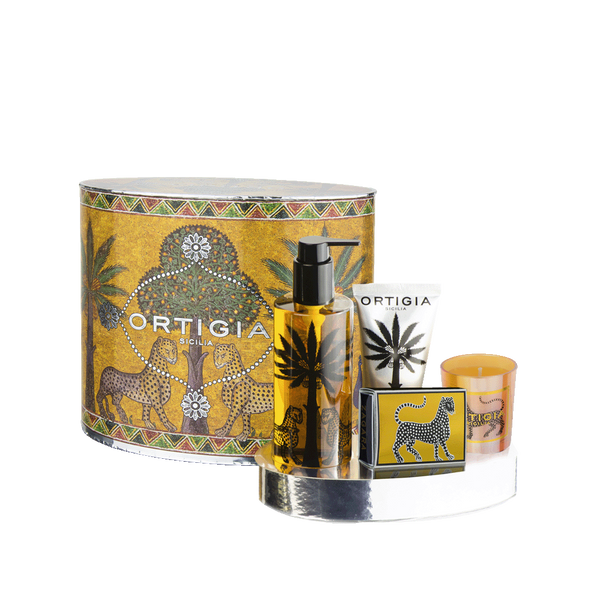 Set de regalo Ortigia con estuche cilíndrico dorado, botella negra y vela naranja.