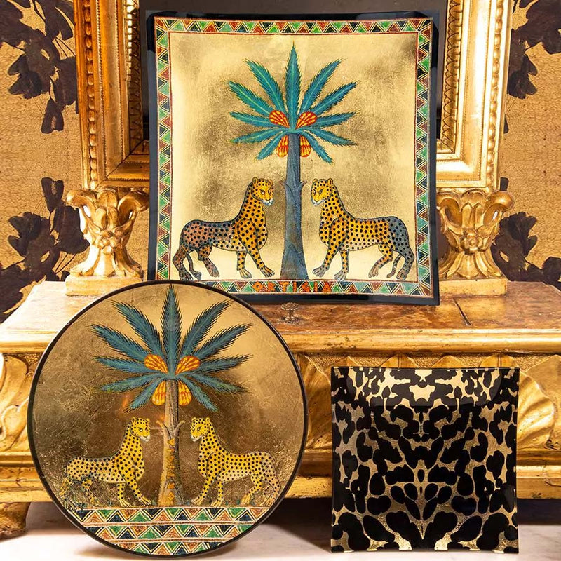 Plato de cristal redondo dorado con palmera azul y felinos atigrados en el centro.