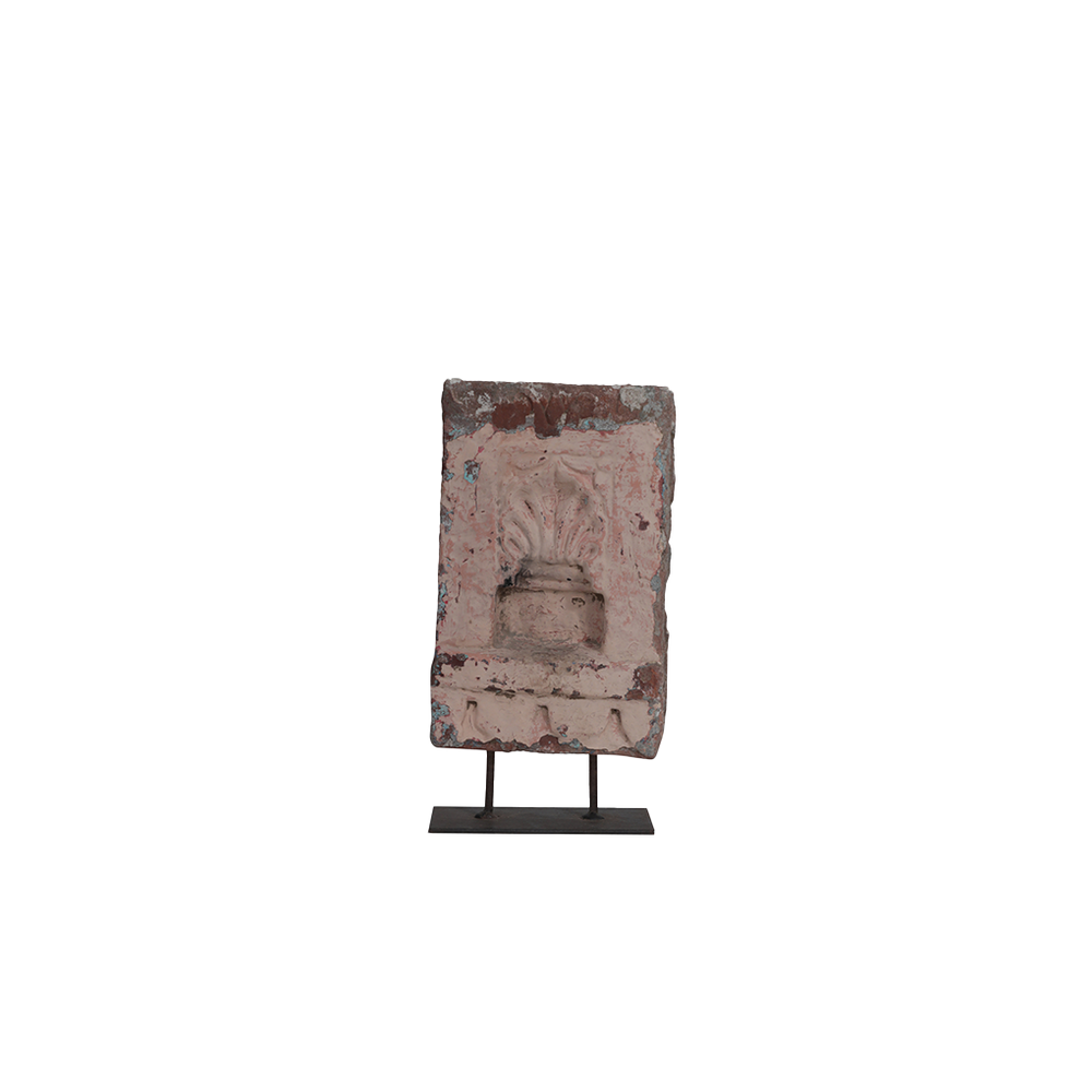 Adorno de piedra rosa en soporte metálico, rostro tallado y textura envejecida