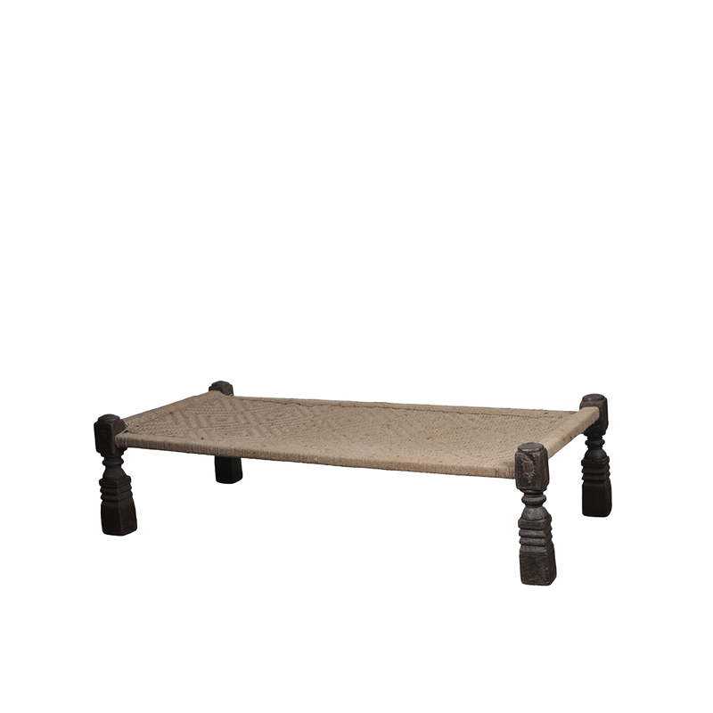 Cama india beige con base tejida y patas torneadas oscuras, vista lateral