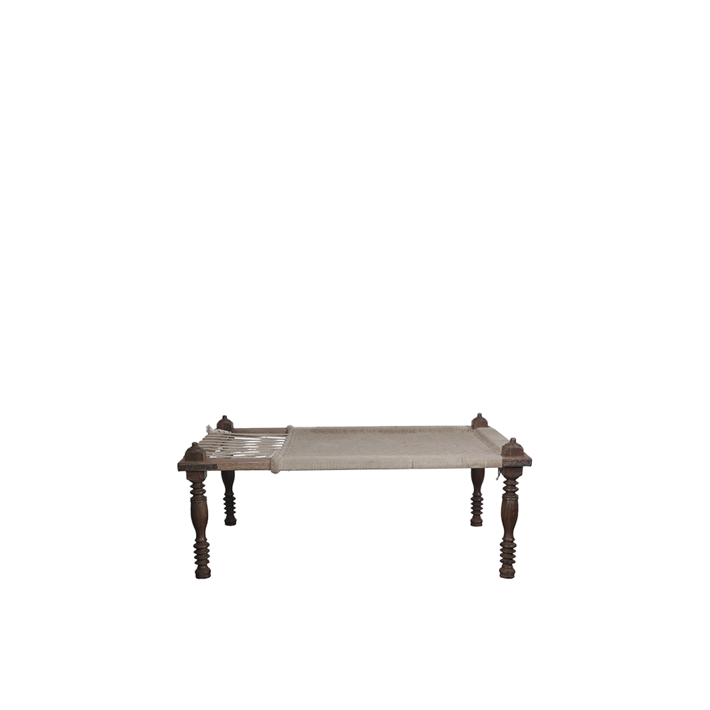 Cama india con estructura de madera oscura y colchón crudo de textura