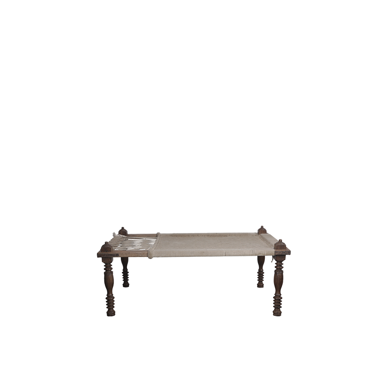 Cama india con estructura de madera oscura y colchón crudo de textura