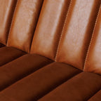Sofá de cuero marrón con asiento acolchado y costuras marcadas