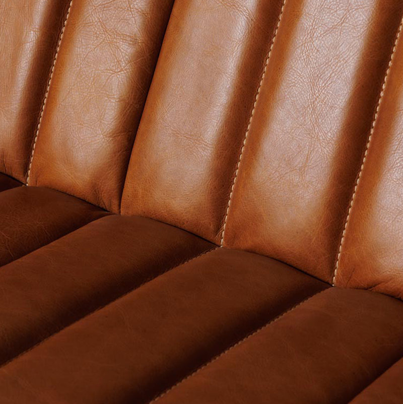 Sofá de cuero marrón con asiento acolchado y costuras marcadas