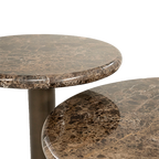 Mesa de centro redonda de mármol marrón; se ve el pie metálico y el canto