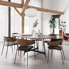 Silla de madera con asiento de piel negra y patas metálicas en ambiente interior.