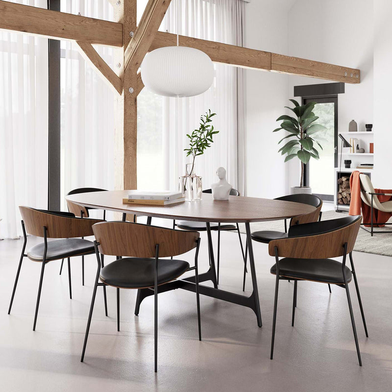 Silla de madera con asiento de piel negra y patas metálicas en ambiente interior.