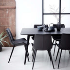 Silla tapizada oscura con respaldo alto y patas negras, vista en interior