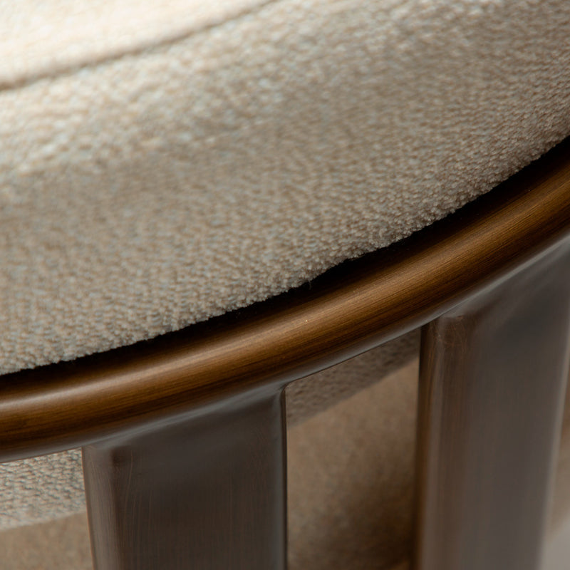 Detalle del tapizado bouclé beige y borde inferior sobre patas de madera oscura