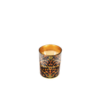 Vela perfumada Ortigia Ambra Nera encendida en vaso con estampado leopardo y flores doradas