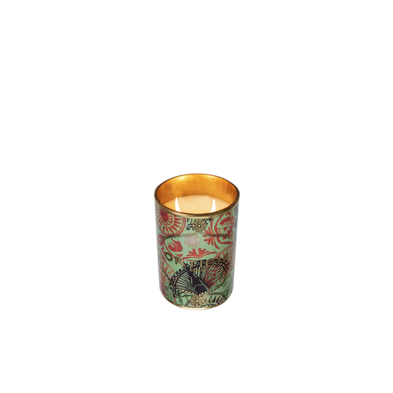Vela aromática en recipiente metálico estampado multicolor con llama encendida