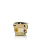 Vela en frasco de fibra tejida beige con flores rojas, amarillas y etiqueta dorada