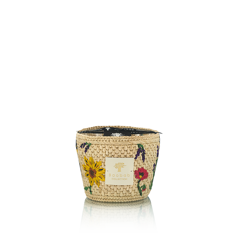 Vela en frasco de fibra tejida beige con flores rojas, amarillas y etiqueta dorada
